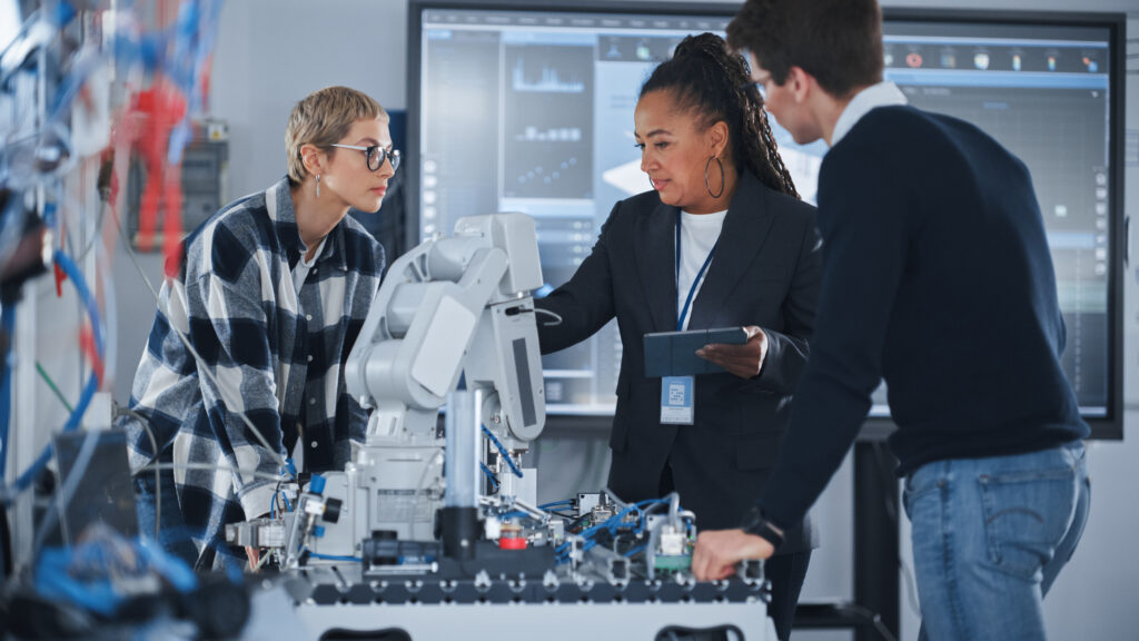 A teacher with students engaged in hands-on activities around a robotic arm.